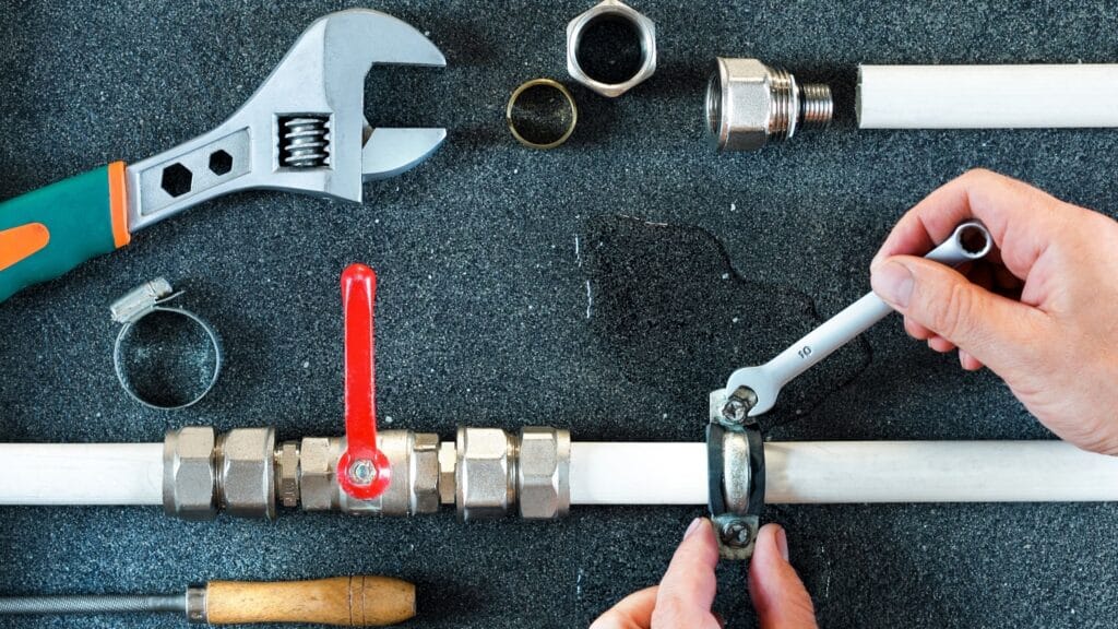 Plumber repairing a pipe valve with an adjustable wrench in Sanford