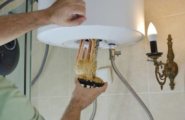 Technician removing mineral buildup from a water heater in Sanford