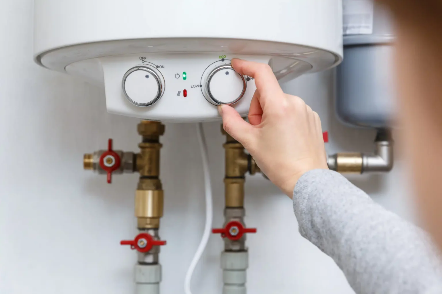 Homeowner adjusting the temperature controls on a water heater in Sanford